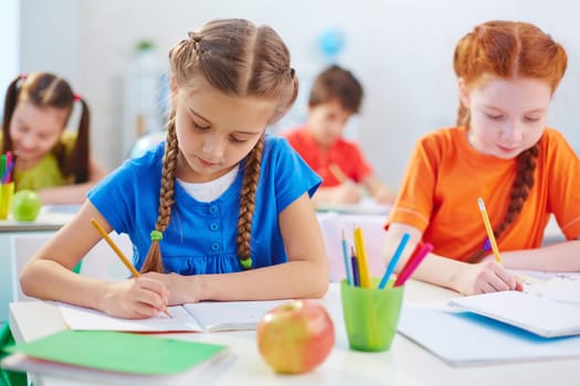 Clever schoolgirls drawing at lesson