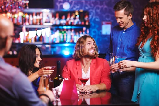 Happy young friends with alcoholic drinks talking at party
