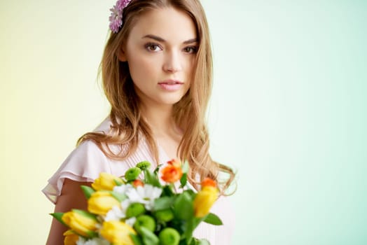 Calm girl with tulips and daisies looking at camera