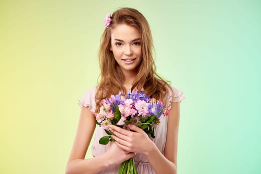 Attractive girl with fresh bouquet looking at camera