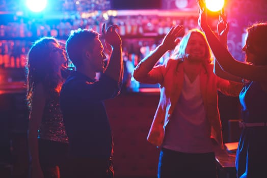 Portrait of happy friends dancing by the bar counter