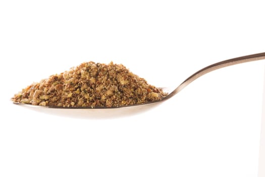 Spoonful of healthy mixed ground nut topping for desserts or salads, isolated on white.