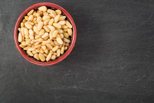 Bowl of pine nuts on a slate surface, view from above with copy space.