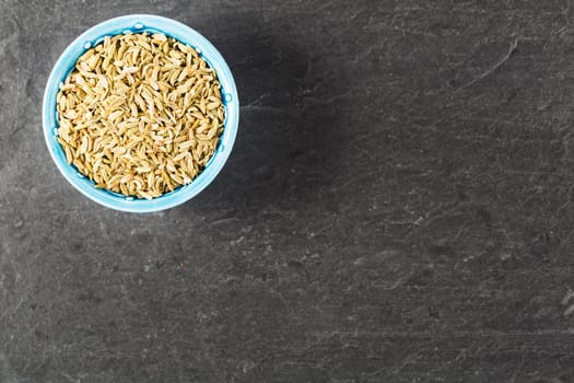 Bowl of fennel seeds on stone surface with copy space.