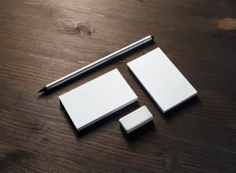 Blank business cards, pencil and eraser on wooden background. ID mockup. Responsive design template.