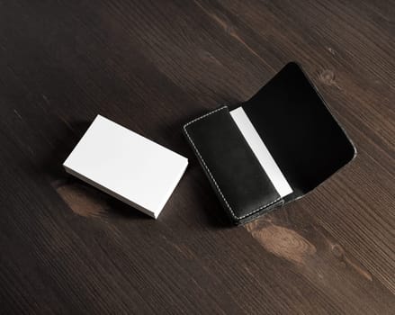 Blank business cards and leather business card holder on wooden background.