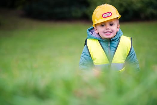 Little cute boy pretending to be a builder foreman outside his home garden