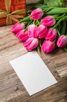 Beautiful bouquet from pink tulips and a gift on a table
