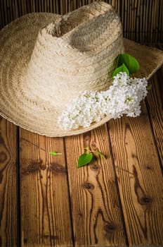 Still-life with a bouquet of lilacs and a straw hat, close-up