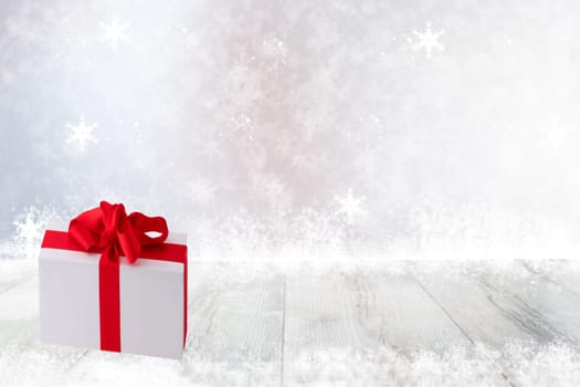Christmas or Happy New Year decoration background. Christmas gift box on bright table top and snowflakes over abstract festive white winter background. Template for your product display montage. Card concept.