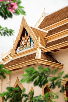 Architectural rooftop detail from exterior view of the Buddhist temple, Wat Traimit over clear sky in Bangkok, Thailand