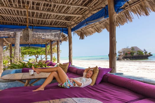 Relaxed woman in luxury tropical bar lounger, enjoying summer vacations on beautiful beach. Lady feeling free, relaxed and happy. Concept of vacations, freedom, happiness, enjoyment and well being.