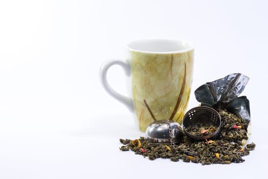 A nice Mug and an open infuser with mango green tea on a white background