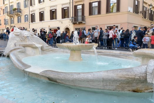 Rome, Italy - November 07, 2015: Tourist admire the amazing fountain called the Barcaccia in Navona square in Rome, Italy