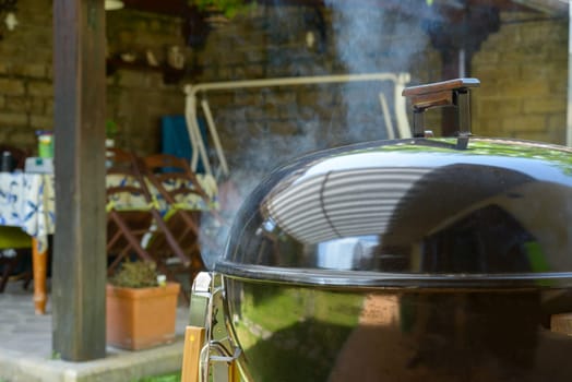Smoke go out from a closed barbecue during pulled pork grill