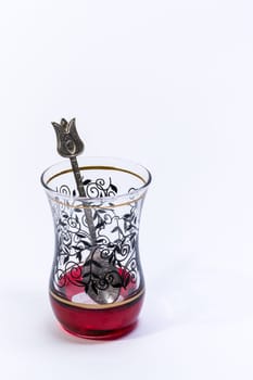 Empty Typical Turkish glass for tea with a teaspoon inside on a white background