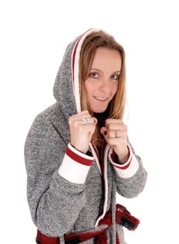 A happy young woman standing in a gray bath robe with the hoody over.her head, smiling, isolated for white background.