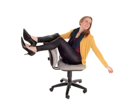 A young woman in black leather pants and a yellow jacket siting on a.office having fun, isolated for white background.