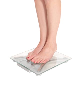 The skinny legs of a young woman standing on a glass scale with red.toes nails, isolated for white background.