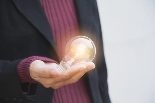 Hand of businesswomean holding light bulb for idea or success or solar energy