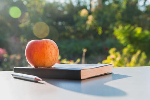 The apple with leather book and pen on nature background with copy space.