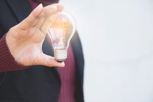 Hand of businesswomean holding light bulb for idea or success or solar energy