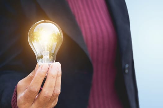 Hand of businesswomean holding light bulb for idea or success or solar energy
