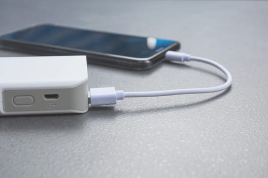 Mobile smart phones charging with power bank on desk.