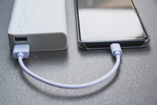 Mobile smart phones charging with power bank on desk.