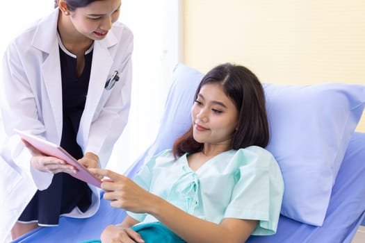 Asian Doctor make routine health check with patient in hospital ward using digital Tablet
