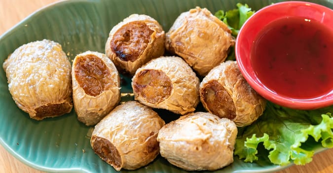 Hoi Jo, Deep Fried Crab Meat Rolls with sweet plum sauce. Thai street food and restaurant cuisine on wooden table. for website banner use.