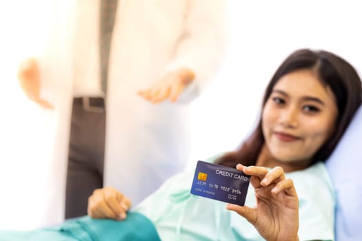 Portrait of Young adult female Patient with credit card in bed of hospital ward