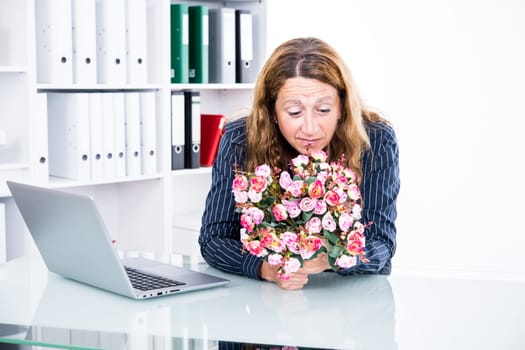 brown-haired  businesswoman in the office with big bouquet of flowers