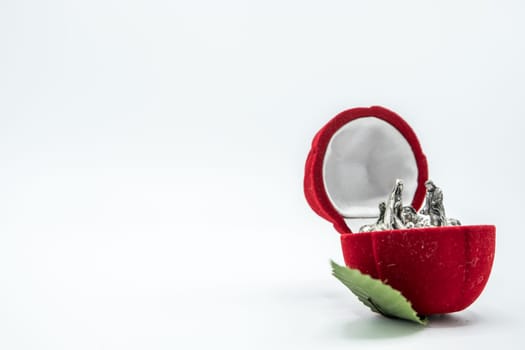 Christian nativity scene silver figures inside a red rose flower jewel velvet box isolated on white background.