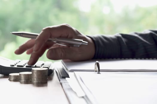 Man using calculator with stock financial indices with stack coin. Financial stock market in accounting market economy analysis.