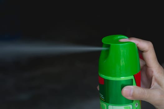 Hand holding mosquito spray. Human using mosquito spray from bottle.