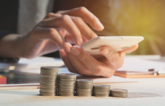 Businesswoman using calculator with stock financial indices with stack coin. Financial stock market in accounting market economy analysis.