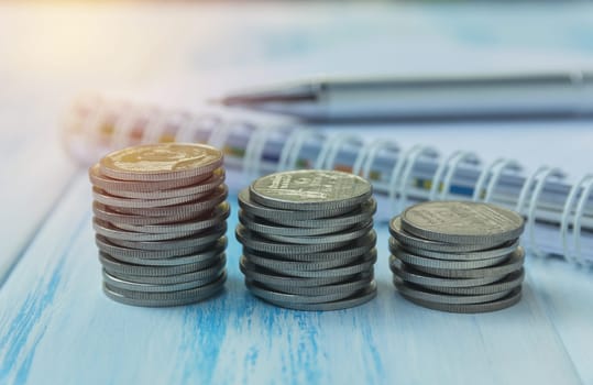 Saving money concept with money coin stack growing and note book for business and accounting concept.