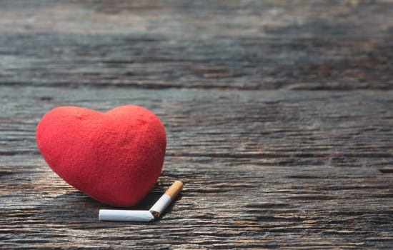Heart and cut off cigarette on wooden background. Protect your health concept.