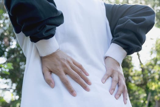 Woman with hands holding her waist back in pain. A woman pain concept.