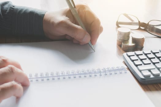 Businessman working and writing on notebook for business and accounting concept.