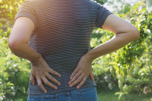 A woman suffering from backache, spinal injury and muscle issue problem at outdoor.