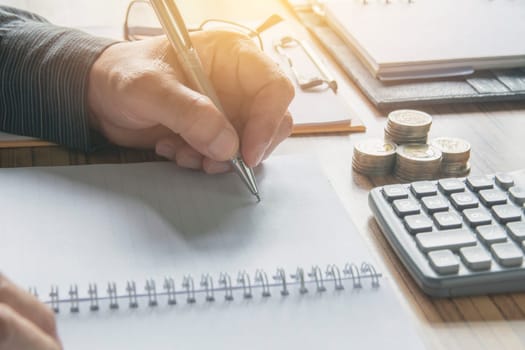 Businessman working and writing on notebook for business and accounting concept.