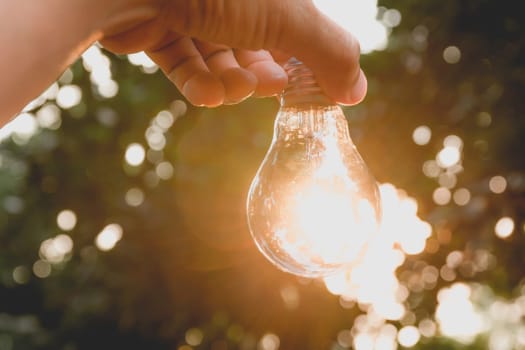 Hand holding light bulbs with glowing on ground. Idea, creativity and saving energy with light bulbs concept.