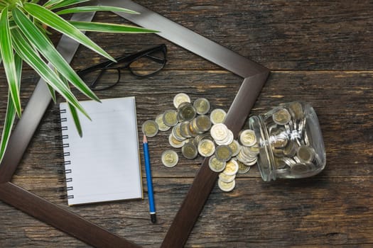 Top view of stack of coin in the frame accounting concept on wooden background.