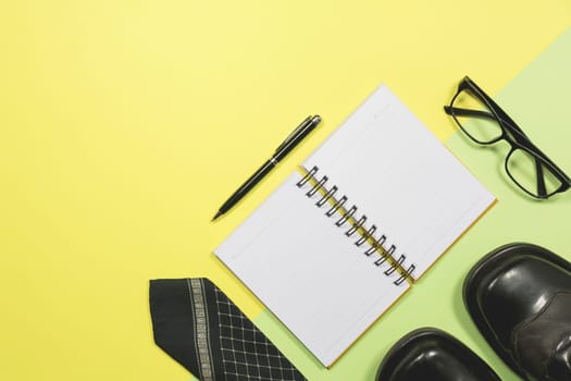 White blank notebook with office supplies on yellow background with copy space for insert text.
