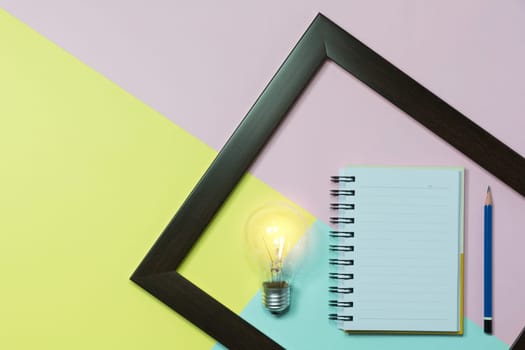 Top view of pencil with light bulb and notebook on colorful background and copy space for insert text.