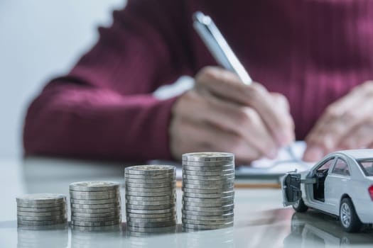 Car insurance and car service. Businesswoman with stack of coins and toy car, business and financial concept.