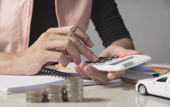 Car insurance and car service. Businesswoman with stack of coins and toy car, business and financial concept.