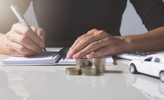 Car insurance and car service. Businesswoman with stack of coins and toy car, business and financial concept.